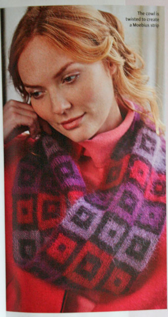 Woman wearing hand-knit purple and pink cowl with a grid pattern