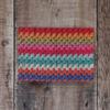 Photo of Granny Stripes greetings card on a wooden background. Greetings card shows detail of some colourful crochet worked in granny stripes