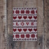 Photo of Love and Hearts greetings card on wooden background. Greetings card shows Fair Isle design featuring hearts, flowers and the word love
