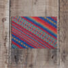 Photo of Painterly greetings card on wooden background. Greetings card shows stitch detail of Painterly, hand-knit shawl