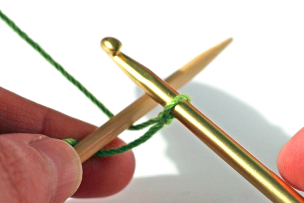 Pass crochet hook over knitting needle