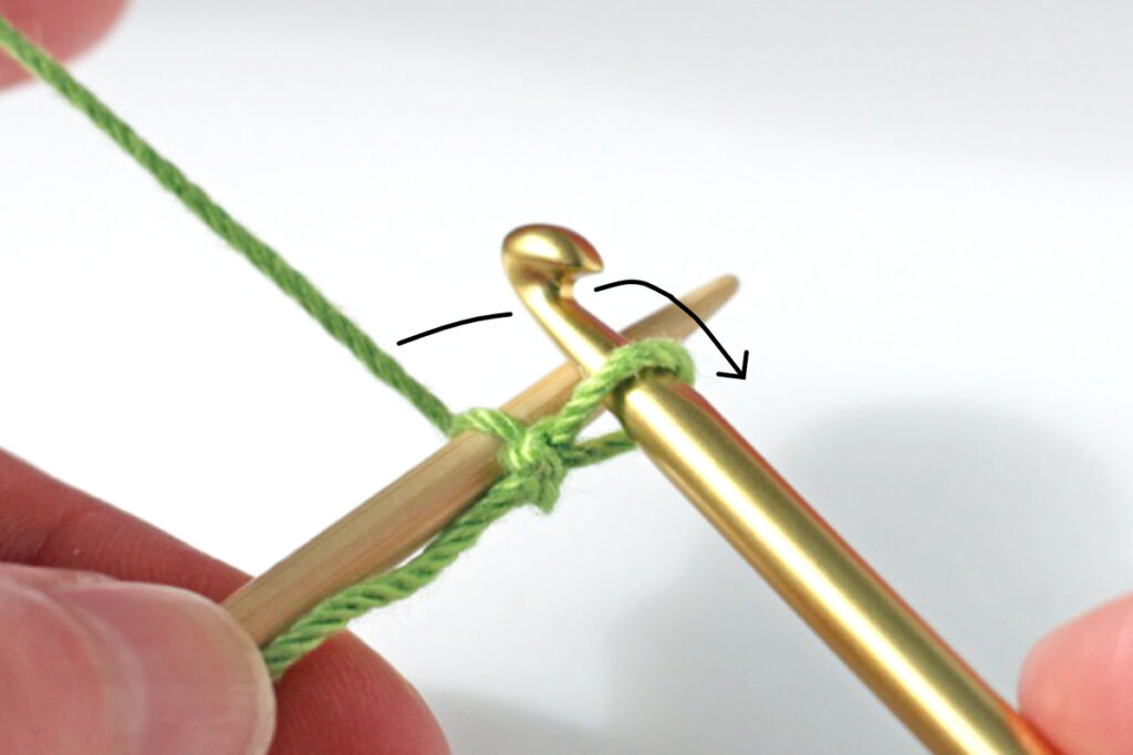 Pass yarn backwards between hook and needle