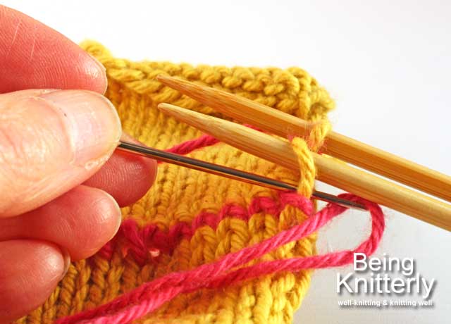 Step 14: Pass yarn needle knitwise through last stitch on front needle and slip off needle