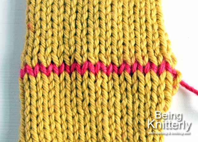 Two pieces of mustard stocking stitch joined by grafting with pink yarn
