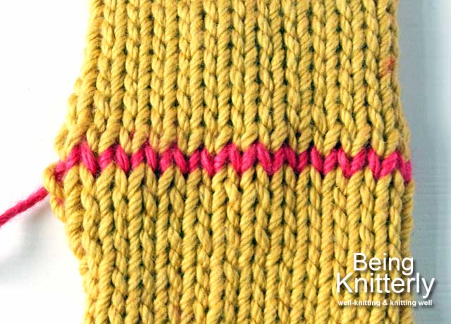 Two pieces of mustard stocking stitch joined by grafting with pink yarn