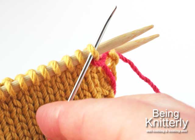 Stitching step 1a: Pass yarn needle knitwise through first stitch on front needle.