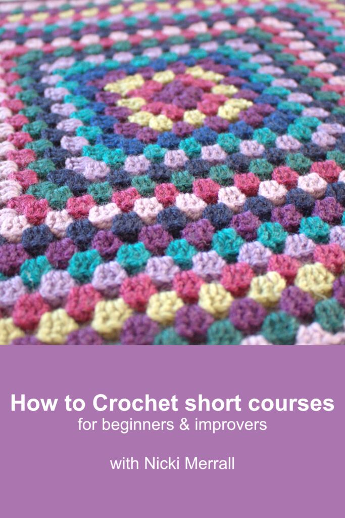 A large granny square crocheted using a wool yarn in many jewel colours