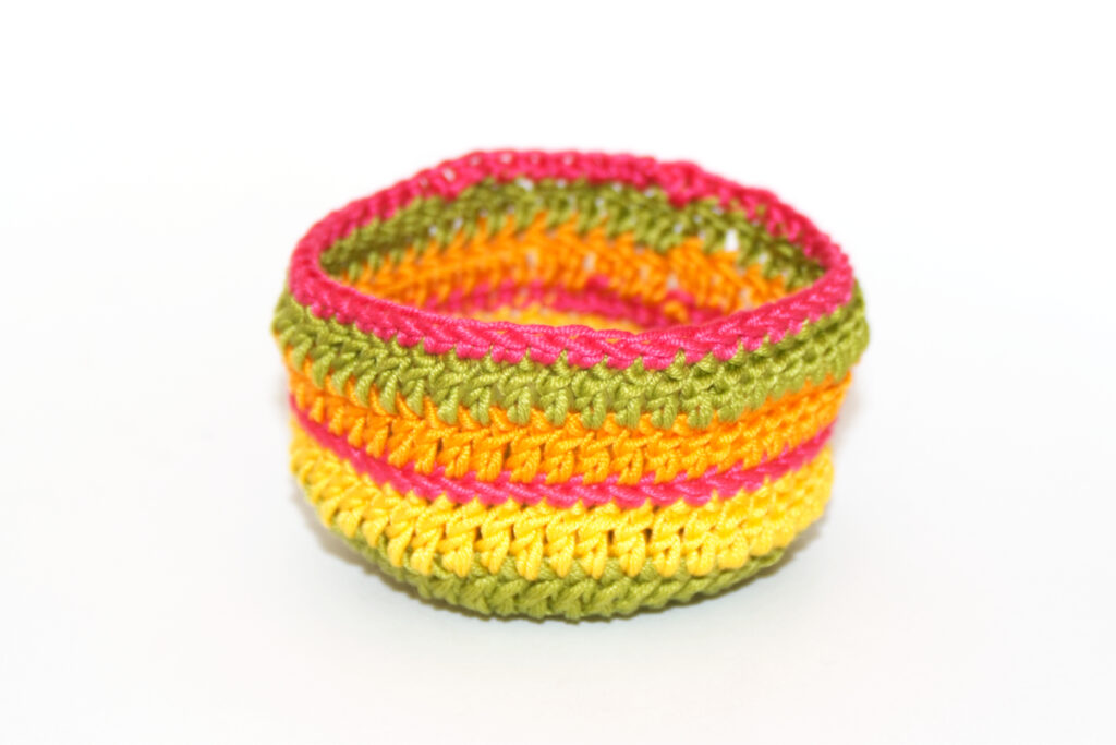 Crochet container worked in deep pink, spring green, orange and yellow cotton yarn.