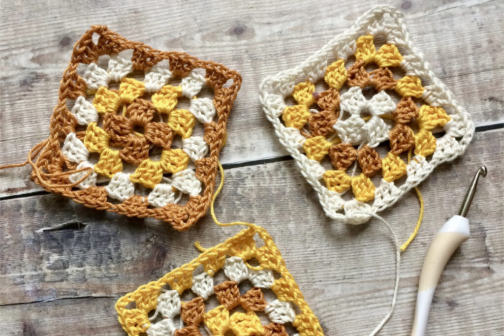 Three granny squares worked using yellow, cream and gold cotton yarn.