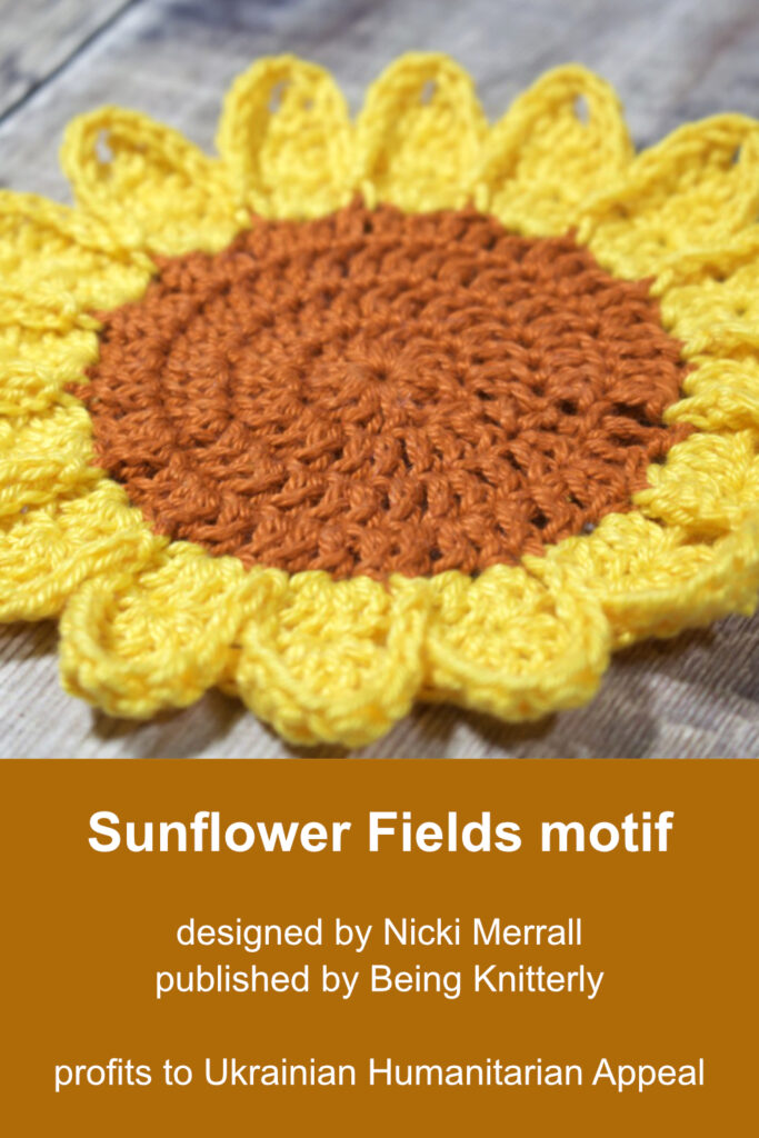 A large crochet sunflower with golden yellow petals and a bright brown centre.